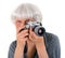 Elderly happy pleasant woman taking pictures with a camera on a white background. Active pension. Leisure and hobbies of people ag