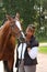 Elderly happy woman and brown horse in the forest