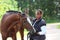 Elderly happy woman and brown horse in the forest