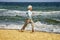 Elderly happy woman running on the beach along the coast near sea