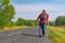 Elderly hiker walking on a roadside in Ukrainian rural area