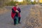 Elderly hiker with walking stick sitting on an old green suitcase on the roadside