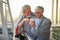 An elderly hugged couple in love warm up with hot tea while enjoying a beautiful sunset from the terrace of their apartment.