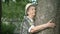 Elderly hugging tree trunk her hands in the forest