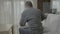 Elderly ill man with rheumatism stretching and massaging his back having a painful cramp -