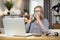 Elderly lady drinking tea while studying report on laptop