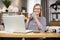 Elderly lady drinking tea while studying report on laptop