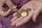 An elderly lady holds a few cents of euro