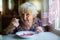 An elderly lone woman eating soup borsch sitting at the table.