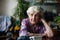 Elderly lone woman portrait sitting in a room.