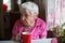 Elderly lone woman with tea mug in the kitchen.