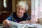 Elderly lone woman watching photos sitting at table.