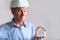 Elderly male agent, a builder in a protective helmet, glasses offers to rent, buy a house, shows a model of a house, a mortgage