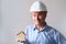 Elderly male agent, a builder in a protective helmet, glasses offers to rent, buy a house, shows a model of a house, a mortgage