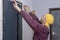 An elderly male construction worker glues a wooden frame to the door. Interior decoration, construction work, apartment repairs.