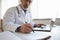 Elderly male doctor fill patient anamnesis in medical journal