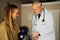 Elderly male doctor gently taking blood pressure from young female patient sitting in doctors office.