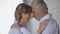 Elderly male and female looking at each other, putting foreheads together, happy