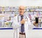 Elderly male pharmacist showing a phone and pointing inside a chemist