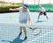 Elderly male player serving ball during training tennis in court outdoors