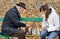 Elderly man arguing during a game of chess with woman sit together on a wooden park bench