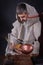 An elderly man with beard in monastic clothing writes scientific work in dark room