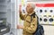 elderly man choosing refrigerator in showroom of electrical appliance store