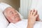 Elderly man with closed eyes lying in hospital bed