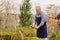 elderly man cuts bushes in the garden with large pruner.