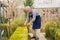 elderly man cuts bushes in the garden with large pruner.