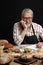 Elderly man demonstrating assortment of bakery. Homemade pastries, rural style