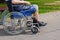 Elderly man with diabetes and kidney disease sitting on wheelchair walking with assistant in the park