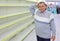 Elderly man at empty shelves in shop scratches