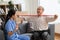Elderly man exercising with resistance band, smiling looking into a caregiver. Therapist serve physical therapy for older patient