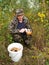 The elderly man gathers mushrooms in the wood