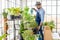 An elderly man with glasses enjoys caring for his plants, watering, spraying, and decorating the plants. It is a hobby of