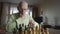 Elderly man with glasses plays chess with himself while sitting at table