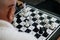 An elderly man with glasses plays special chess for the blind