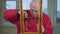 Elderly man in glasses and with screwdriver in hands repairs wooden stool