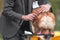 Elderly man in a gray suit combing a Pomeranian on a grooming table during a dog show