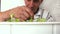 An elderly man grows horticultural crops in a flower pot at home. The pensioner takes care of house plants. Selective focus, man f