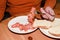 Elderly man holding fork and eating smoked salmon with slice of white bread. Solitude and single concept.