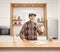 Elderly man holding a glass of milk and standing behind a wooden counter in a kitchen