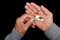 An elderly man holds a lot of colored pills in old hands on a dark background. Painful old age. Health care of older people.