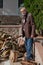 Elderly man in jacket stands in front of pile firewood