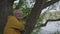 Elderly man leans crossed arms on tree trunk watching nature