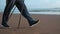 Elderly man legs Scandinavian walking stick healthy lifestyle sport hobby at sea sand beach closeup