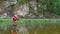 An elderly man with long hair and a santa claus beard stands in the water and holds a fishing rod. Fly fishing