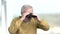 Elderly man looking through binoculars.