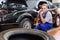 Elderly man mechanic engaged in replacement of car wheel in auto workshop